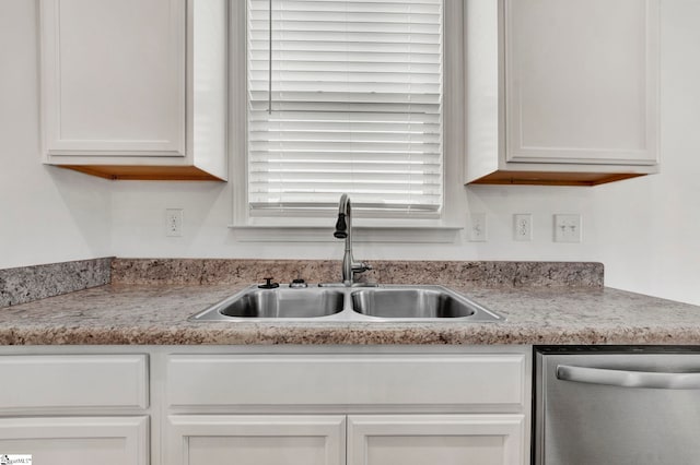 kitchen with stainless steel dishwasher, white cabinetry, and sink