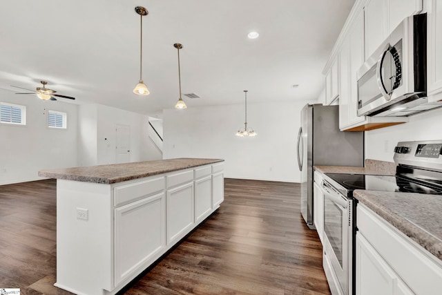 kitchen with stainless steel appliances, white cabinets, hanging light fixtures, dark hardwood / wood-style floors, and a kitchen island