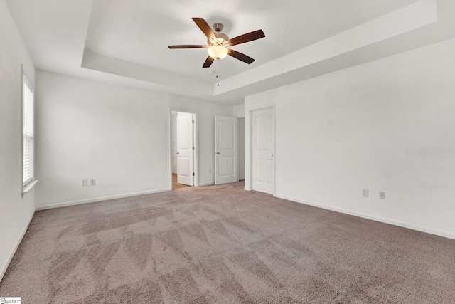 carpeted spare room with ceiling fan and a raised ceiling