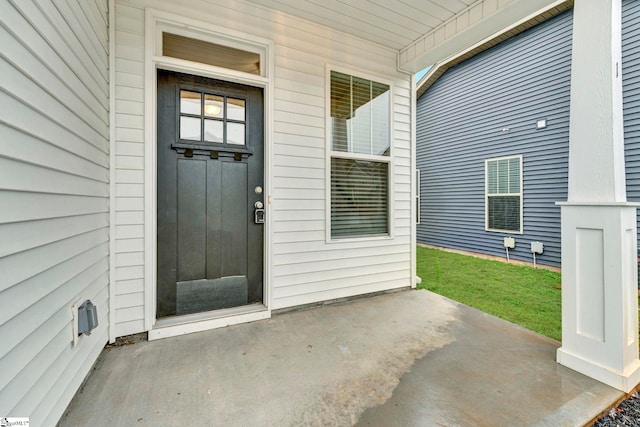 view of exterior entry with a yard and a patio