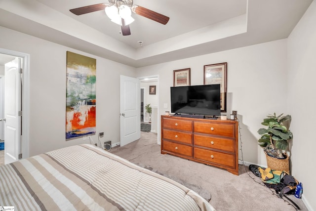 carpeted bedroom with a tray ceiling and ceiling fan