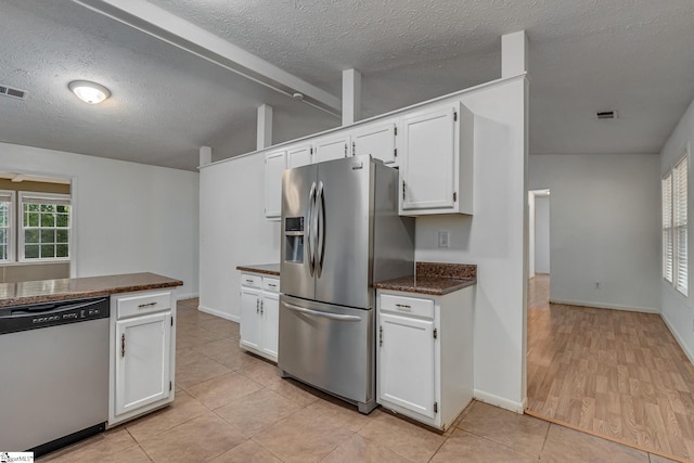 kitchen featuring light tile patterned flooring, white cabinets, stainless steel appliances, and a textured ceiling