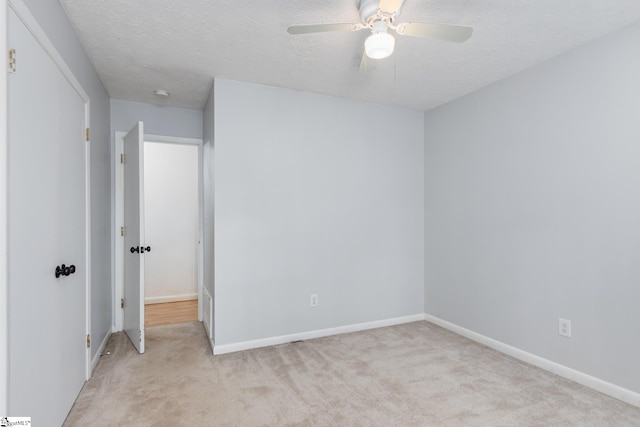 spare room with light carpet, ceiling fan, and a textured ceiling