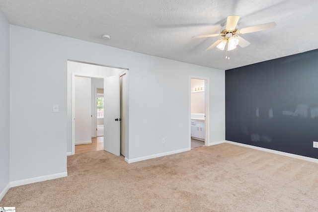 unfurnished bedroom featuring a textured ceiling, ceiling fan, light colored carpet, and ensuite bathroom