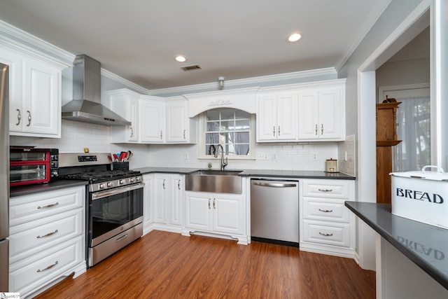 kitchen featuring stainless steel appliances, wall chimney exhaust hood, white cabinets, and sink