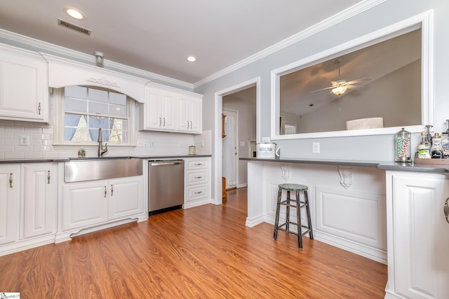 kitchen featuring a kitchen bar, light hardwood / wood-style floors, dishwasher, white cabinets, and crown molding