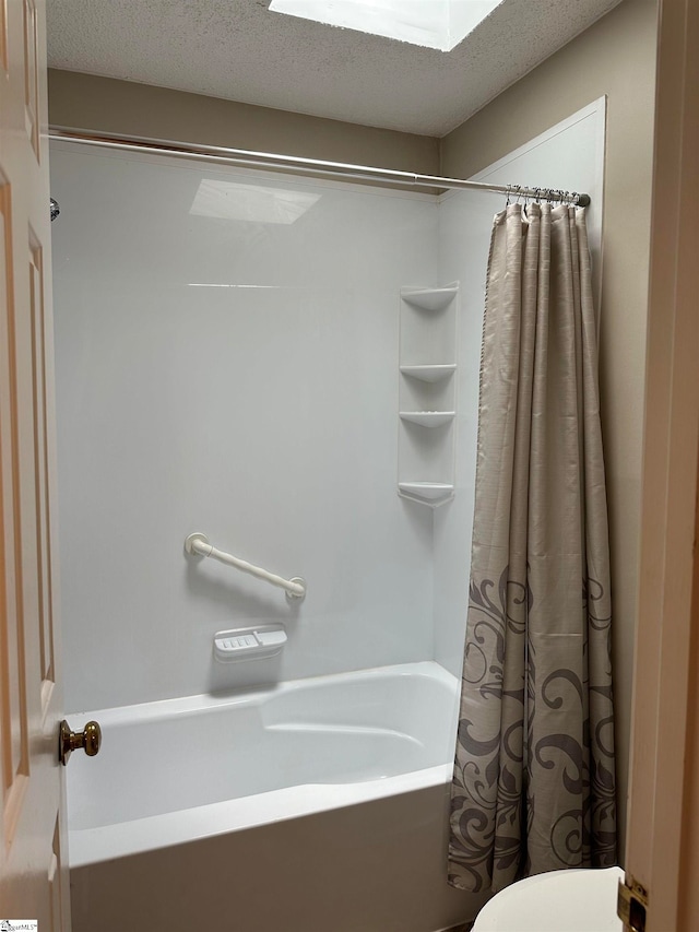 bathroom with a textured ceiling, toilet, and shower / tub combo