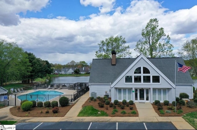 view of pool featuring central air condition unit and a water view