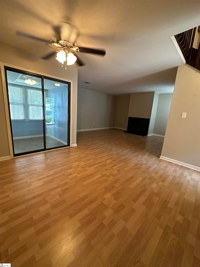 unfurnished living room with a textured ceiling, light hardwood / wood-style floors, and ceiling fan