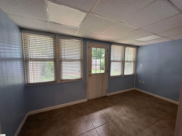 unfurnished room featuring a drop ceiling and dark tile patterned flooring