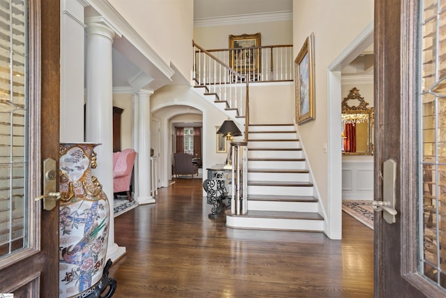 entryway featuring ornate columns, dark wood-type flooring, and crown molding