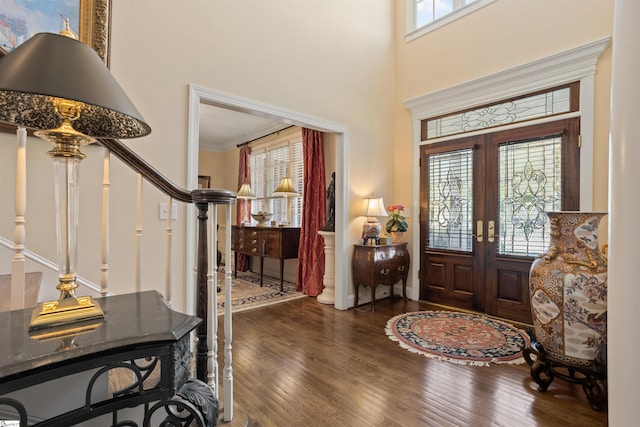 foyer entrance featuring dark wood-type flooring, french doors, a high ceiling, and crown molding