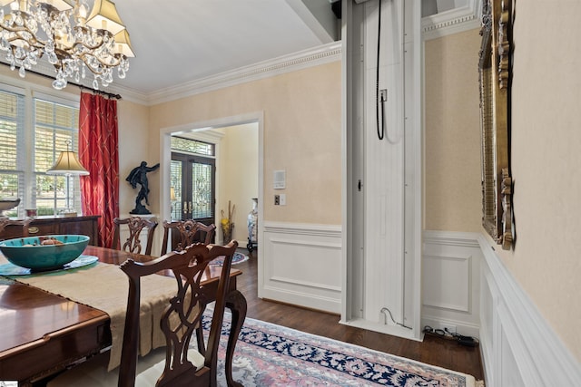 dining room with dark wood-type flooring, ornamental molding, an inviting chandelier, and a healthy amount of sunlight