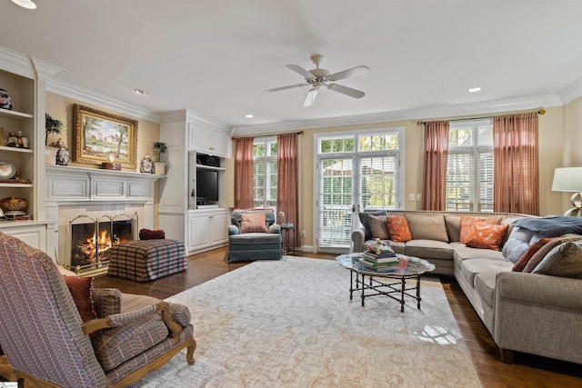 living room with built in features, dark hardwood / wood-style floors, crown molding, and ceiling fan