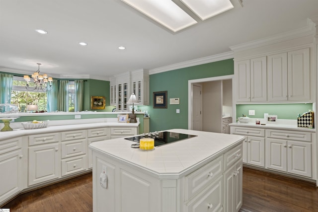 kitchen with white cabinets, black electric stovetop, ornamental molding, and a center island