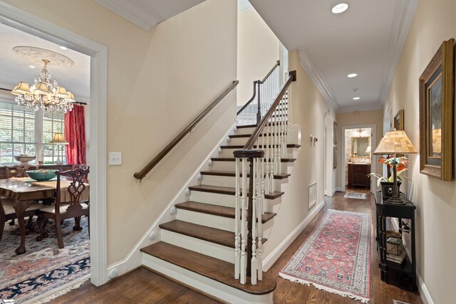 stairs featuring an inviting chandelier, hardwood / wood-style flooring, and ornamental molding