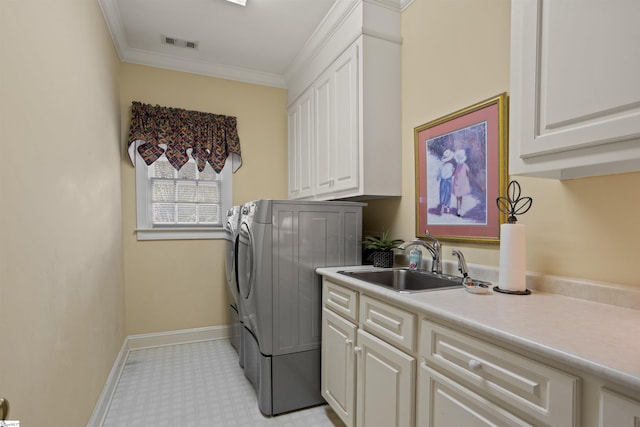 laundry area featuring crown molding, washing machine and dryer, cabinets, and sink