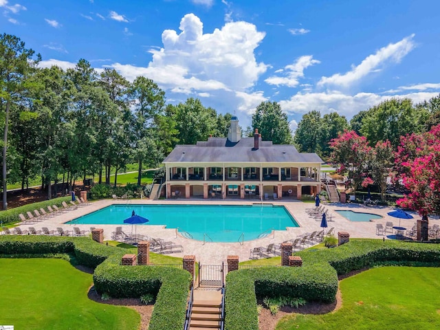 view of pool with a lawn, a hot tub, and a patio area