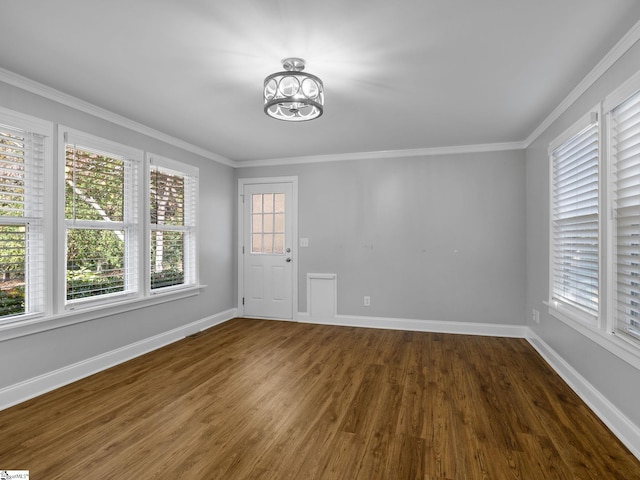 spare room featuring ornamental molding, dark wood-type flooring, and a chandelier