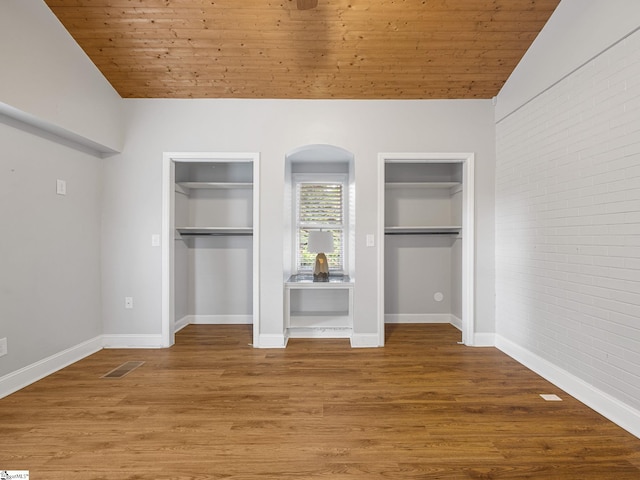 unfurnished bedroom with hardwood / wood-style floors, wooden ceiling, and two closets