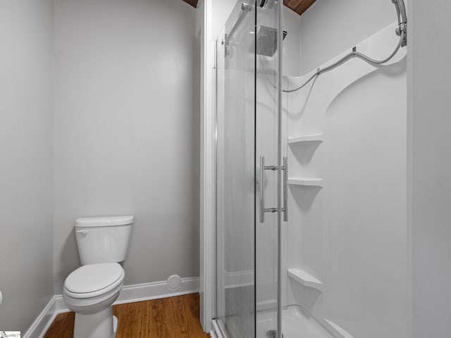 bathroom with hardwood / wood-style floors, toilet, and a shower with shower door