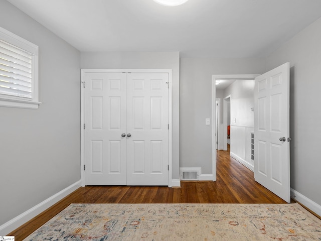 unfurnished bedroom featuring a closet and dark hardwood / wood-style floors