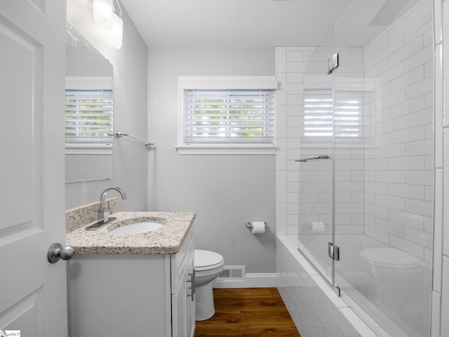 bathroom with a wealth of natural light, hardwood / wood-style flooring, toilet, and a shower with door