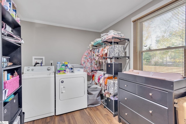 laundry area with washing machine and clothes dryer, wood-type flooring, and crown molding