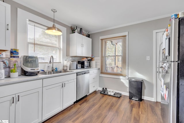 kitchen with white cabinetry, appliances with stainless steel finishes, dark hardwood / wood-style floors, hanging light fixtures, and sink