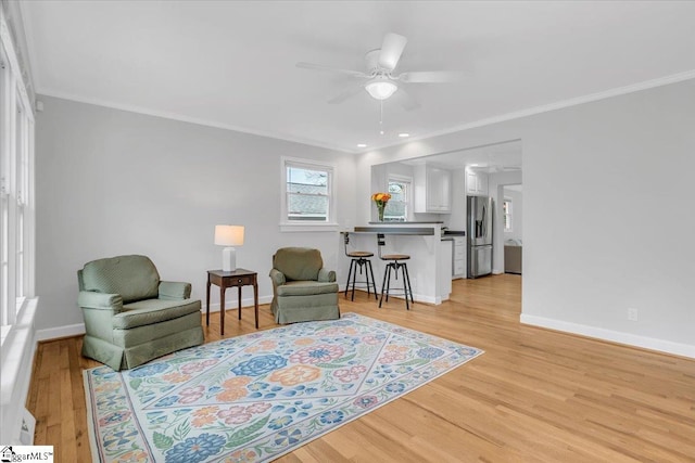 sitting room with light wood-type flooring, ceiling fan, and ornamental molding