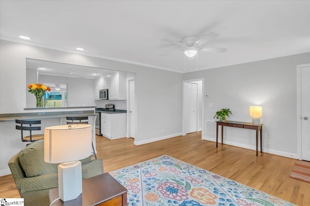 living room with ceiling fan, light hardwood / wood-style flooring, and ornamental molding