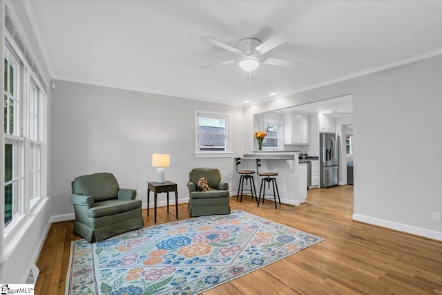 living area featuring light hardwood / wood-style floors, ceiling fan, and crown molding