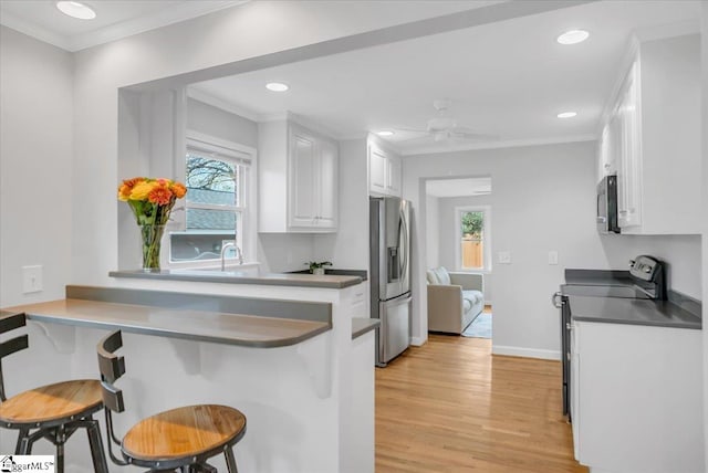 kitchen with stainless steel appliances, white cabinetry, kitchen peninsula, a breakfast bar area, and light hardwood / wood-style flooring