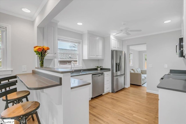 kitchen featuring light hardwood / wood-style floors, stainless steel appliances, kitchen peninsula, sink, and white cabinetry