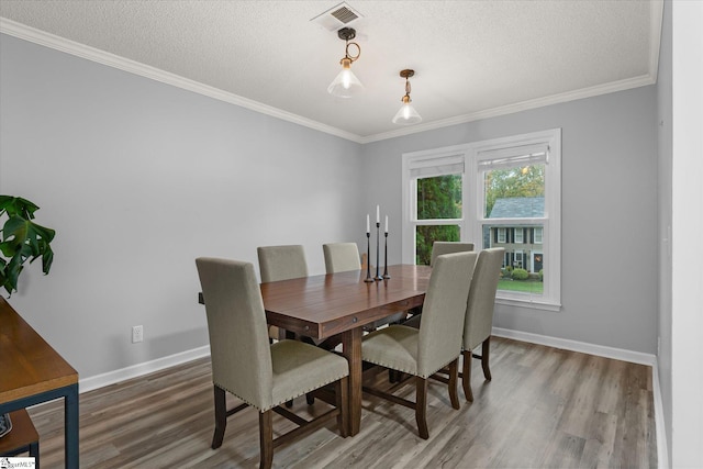 dining room with hardwood / wood-style floors, crown molding, and a textured ceiling