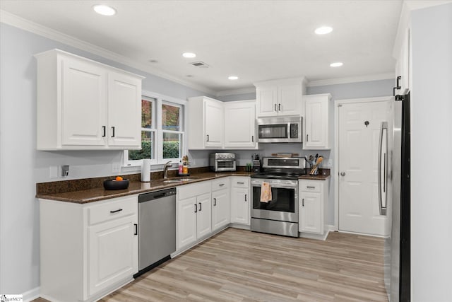 kitchen with white cabinets, sink, ornamental molding, and stainless steel appliances