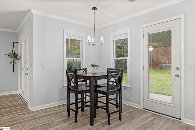 dining room featuring hardwood / wood-style floors, a healthy amount of sunlight, crown molding, and a chandelier