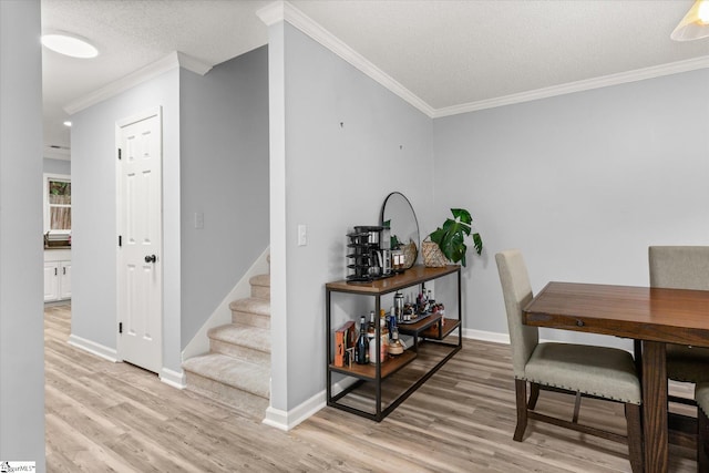 interior space with light wood-type flooring, a textured ceiling, and ornamental molding