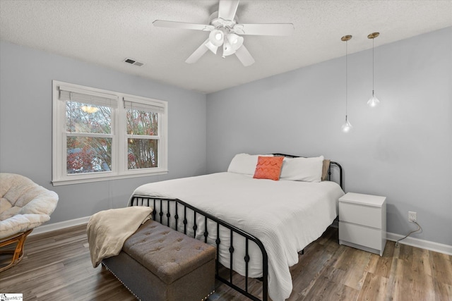 bedroom with ceiling fan, dark hardwood / wood-style flooring, and a textured ceiling