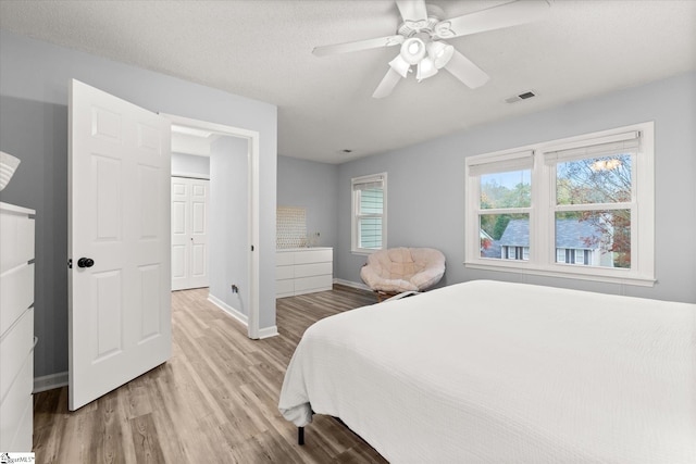 bedroom with a textured ceiling, light hardwood / wood-style floors, and ceiling fan