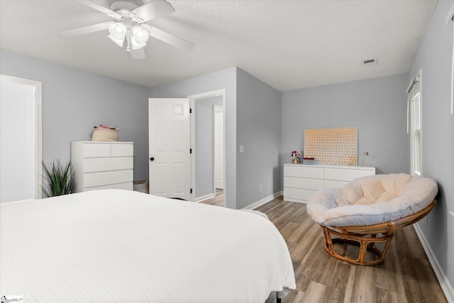 bedroom featuring hardwood / wood-style floors, ceiling fan, and a textured ceiling