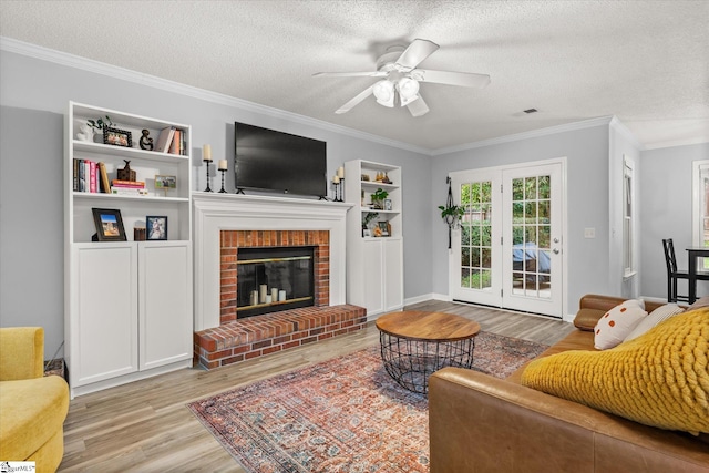 living room featuring a fireplace, ceiling fan, ornamental molding, and a textured ceiling