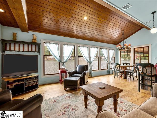 living room with lofted ceiling with beams, light hardwood / wood-style floors, a chandelier, and wood ceiling