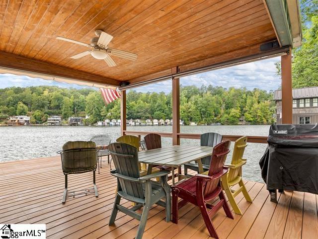 wooden terrace with a water view and ceiling fan