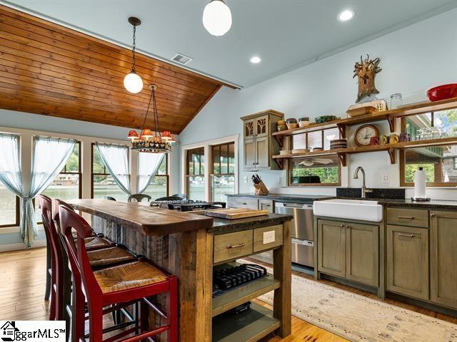 kitchen with a wealth of natural light, sink, vaulted ceiling, and a kitchen breakfast bar