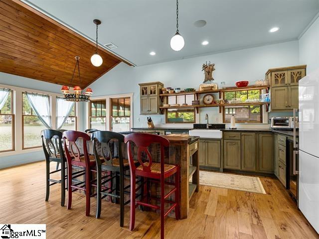 kitchen with light wood-type flooring, white refrigerator, hanging light fixtures, a chandelier, and lofted ceiling