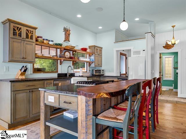 kitchen with light hardwood / wood-style floors, dark stone counters, hanging light fixtures, a center island, and dishwasher