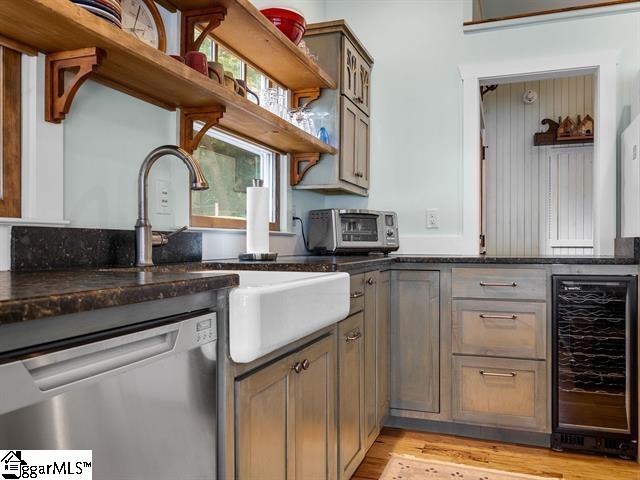 kitchen with sink, dark stone countertops, beverage cooler, light hardwood / wood-style flooring, and dishwasher