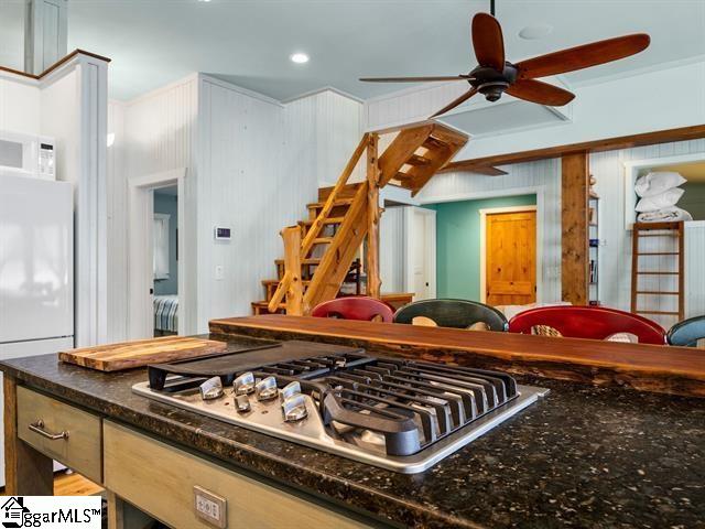 kitchen featuring light brown cabinetry, ceiling fan, and white appliances