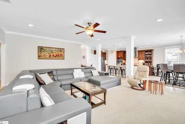 living room featuring ceiling fan with notable chandelier, light colored carpet, ornate columns, and crown molding